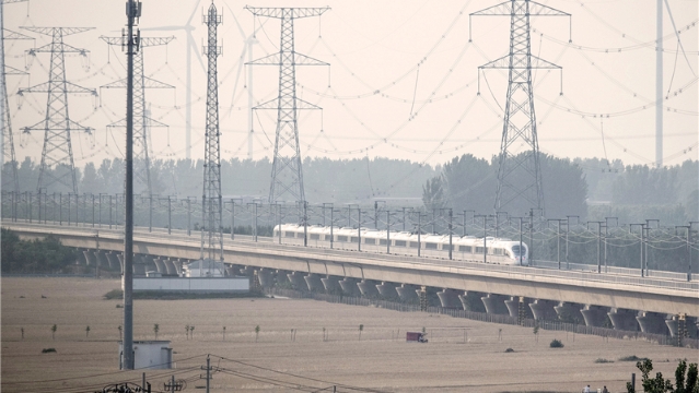 高铁列车行进在金色麦海